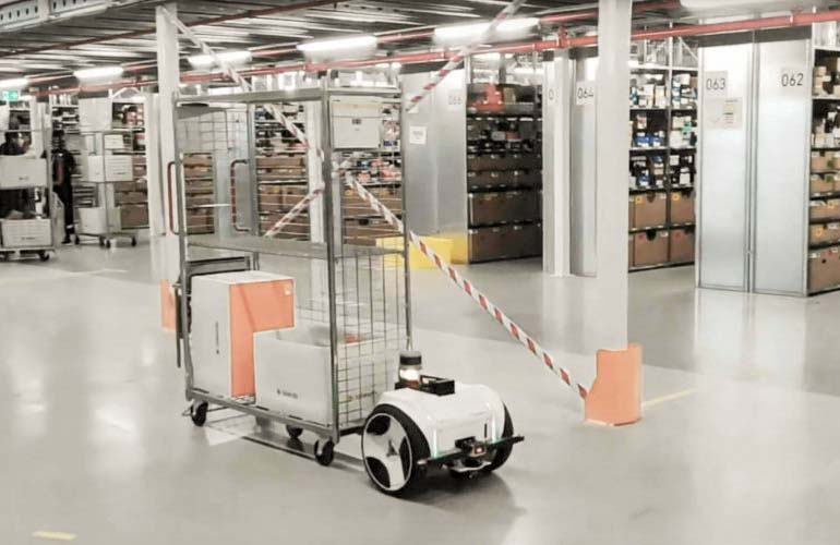 a mov.ai AMR pulls a cart of material in a factory