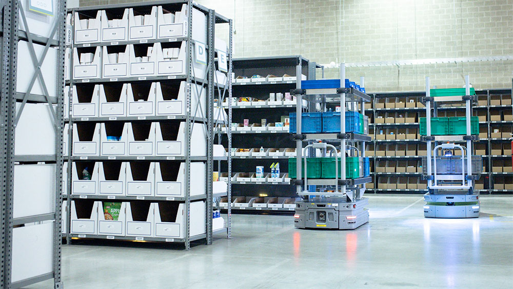 Two IAM Robotics Lumabots move items through a warehouse.